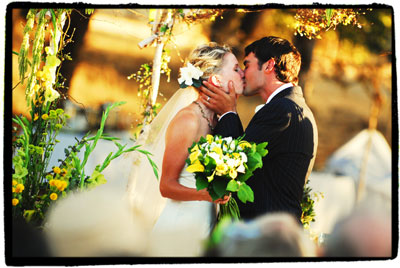 Bride and Groom kiss under arch of flowers allyson_rich_006