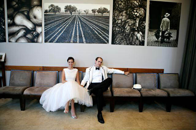Bride and groom sitting in front of art