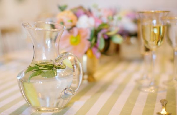 Citrus Bridal Shower, green striped tablecloth, water vase, gold trimmed glasses, gold vases